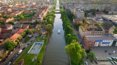 Romanya 'nın Timisoara kentindeki Bega Nehri' nin insansız hava aracı görüntüsü. Nehrin her iki yakasında yüzen tekne, yeşillik ve tarihi yapılar olan nehir manzarası ve köprüler