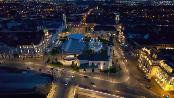 ルーマニアの夜にダウンタウンのOradeaのUnirii Squareの実際のドローンビュー フェルディナンド1世像 聖ラディスラウス教会 市庁舎 その他の歴史的建造物 — ストック動画