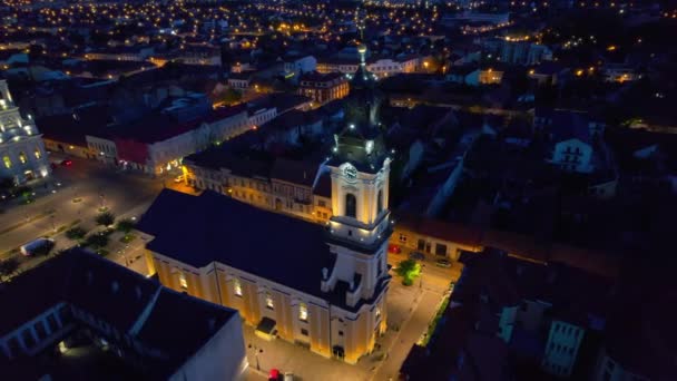 ルーマニアの夜にダウンタウンのOradeaのUnirii Squareの実際のドローンビュー 聖ニコラス大聖堂 周辺の複数の建物 — ストック動画