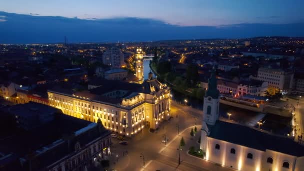 ルーマニアの夜にダウンタウンのOradeaのUnirii Squareの実際のドローンビュー 聖ラディスラウス教会と市庁舎 — ストック動画