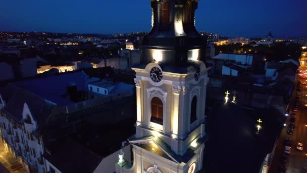 ルーマニアの夜にダウンタウンのOradeaにあるMoon Churchの実際のドローンビュー 歴史的建造物やライトアップされた車 — ストック動画