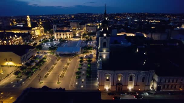 ルーマニアの夜にダウンタウンのOradeaのUnirii Squareの実際のドローンビュー 月の教会 聖ニコラス大聖堂やその他の歴史的建造物 — ストック動画