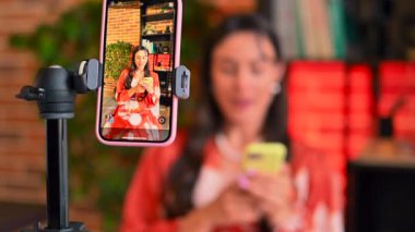 Kırmızı elbiseli kadın etkileyicisi cep telefonunda vlog yapıyor