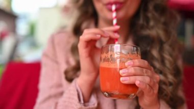 Restoranın terasında taze havuç suyu içen bir kadın.