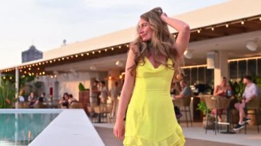 Sarı elbiseli kadın İspanya 'da havuz kenarında dans ediyor.