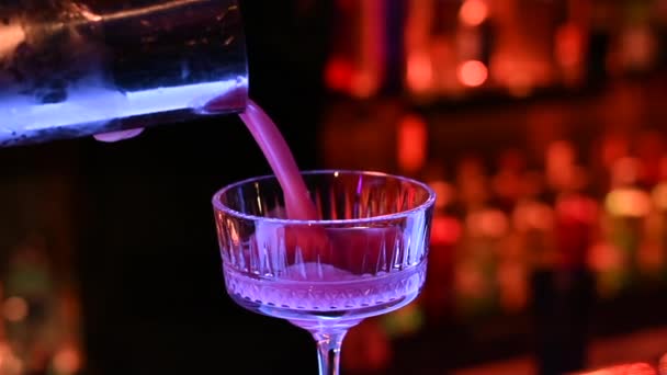 バーマンがナイトクラブのバーのガラスに紫色のカクテルを注ぎ スローモーション — ストック動画