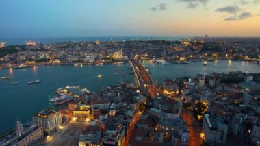 Türkiye 'de gün batımında İstanbul' un hava aracı görüntüsü. Birden fazla bina, camiler, Golden Horn su yolu üzerindeki Galata köprüsü. Birden fazla yüzen gemi, gece lambaları.