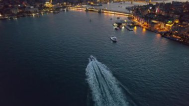 Türkiye 'de gün batımında İstanbul' un hava aracı görüntüsü. Birden fazla bina, cami, Galata ve Metro köprüsü. Golden Horn su yolu üzerinde çok sayıda yüzen gemi ve gece lambası var.