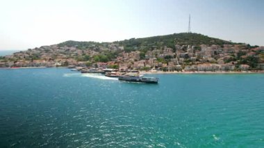 Kinaliada, Türkiye 'nin hava aracı görüntüsü. İnsanlarla birlikte yüzen gemi, arka planda Marmara Denizi kıyısında bulunan birden fazla meskun bina.