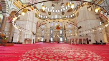 İstanbul, Türkiye 'deki Süleyman Camii' nin iç manzarası. Bir sürü aydınlatma, boyanmış tavan, kırmızı halı.