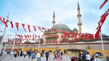 İSTANBUL, TURKEY - 5 HAZİRAN 2023: Arka planda çok sayıda yürüyen insan, ulusal bayraklar ve Taksim Camii bulunan Cumhuriyet Anıt Parkı