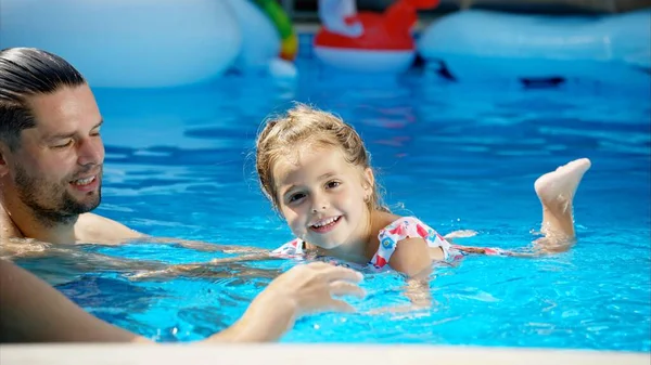 サングラスの小さな女の子は 父親とプールで泳ぐことを学びます — ストック写真