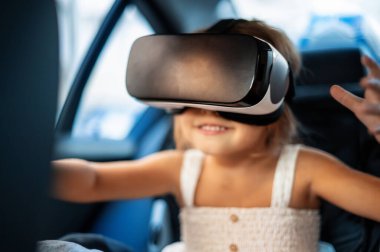 VR gözlükleriyle çocuk emniyet koltuğunda oturan küçük kız.