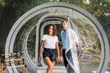 Şeffaf kabarcık çadırına giren bir çift. Çevredeki yemyeşil orman ve doğa