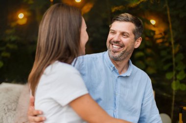 Yatakta otururken şeffaf kabarcık çadırında kucaklaşan bir çift. Arka planda yemyeşil orman