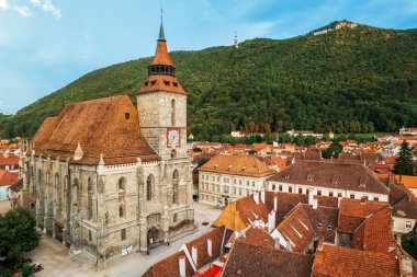 Romanya 'nın eski Brasov merkezindeki Kara Kilise' nin insansız hava aracı görüntüsü. Çevresindeki eski binalar, yeşillikli tepeler.