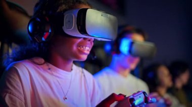 Beyaz çocuk ve siyah kız, video oyunu kulübünde video oyunu oynayan, video oyunu oynayan, oyun alanı kullanan, video oyunu oynayan genç kızlar.