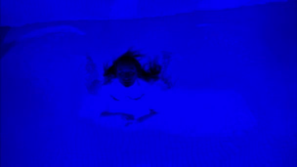 夜にネオンライトが付いている暗い青いプールで甘い女性 — ストック動画