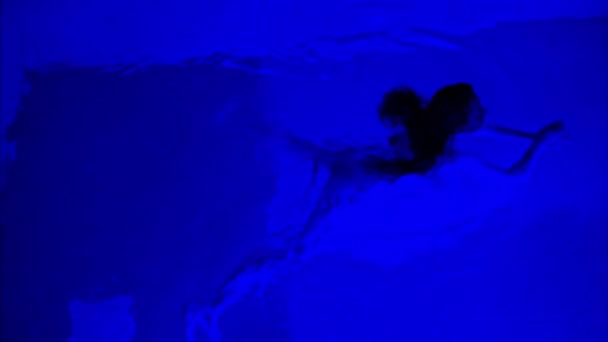女人在深蓝色的池子里甜甜的 旁边有霓虹灯 — 图库视频影像