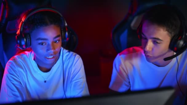 Λευκό Αγόρι Και Μαύρο Κορίτσι Έφηβοι Ακουστικά Συζητώντας Ενώ Παίζουν — Αρχείο Βίντεο