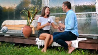 Şarap içen mutlu bir çift Glamping 'de şeffaf kabarcık çadırının yanında konuşuyor. Yavaş çekim