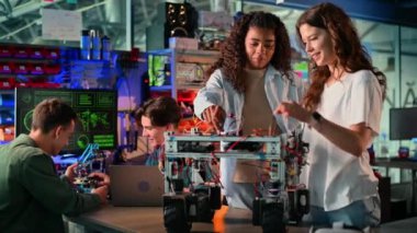Bir laboratuvarda robotik deneyler yapan bir grup genç. Robot ve aletler masada.