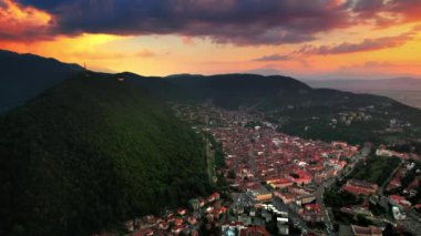 Romanya 'nın güneş doğarken Brasov' un insansız hava aracı görüntüsü. Eski binalarla dolu eski şehir merkezi, yeşilliklerle kaplı tepeler