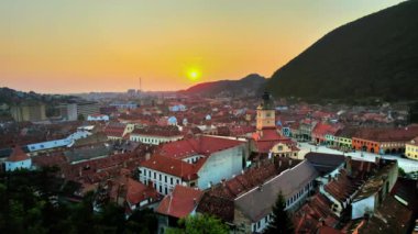 Romanya 'nın güneş doğarken Brasov' un insansız hava aracı görüntüsü. Konsey Meydanı 'nın olduğu eski şehir merkezi, yeşillikle kaplı eski binalar ve tepeler.