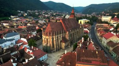 Romanya 'nın başkenti Brasov' un merkezindeki Kara Kilise 'nin hava aracı görüntüsü. Çevresindeki eski binalar, yeşillikli tepeler.