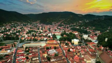 Romanya 'nın gün batımında Brasov' un insansız hava aracı görüntüsü. Eski binalarla dolu eski şehir merkezi, yeşilliklerle kaplı tepeler