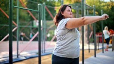 Kilolu, gri tişörtlü ve taytlı bir kadın spor sahasında kilo vermek için spor yapıyor. Fitness yaşam tarzı