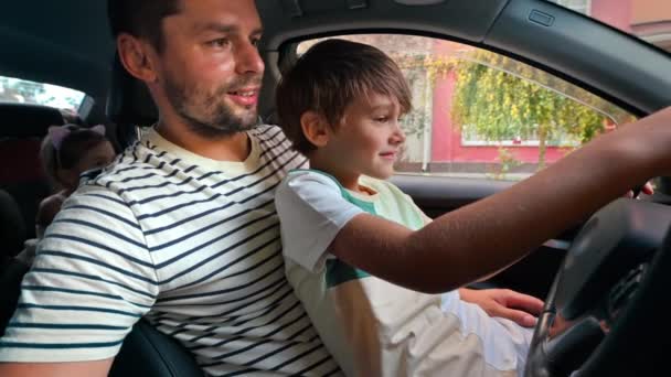 Ojciec Uczy Syna Jak Prowadzić Samochód Kolanach Pokazuje Znak Pokoju — Wideo stockowe