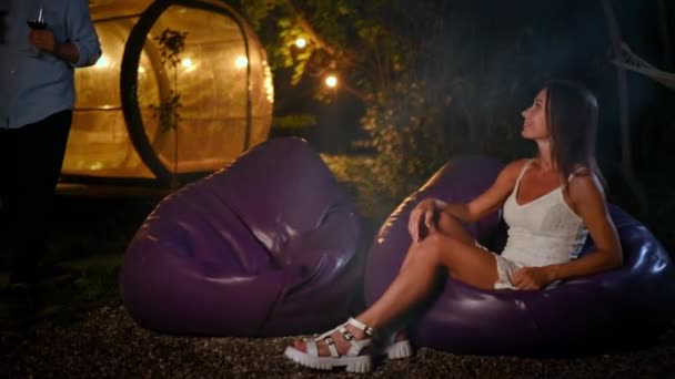 一对快乐的夫妇晚上喝酒 在壁炉边聊天 透明的泡沫帐篷在釉面的背景上 — 图库视频影像