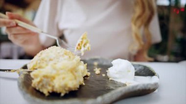 Kafede çatalla dondurma yiyen bir kadının yakın görüntüsü.