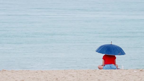 Vista Una Mujer Soltera Bajo Paraguas Sentada Una Playa Movimiento — Vídeos de Stock