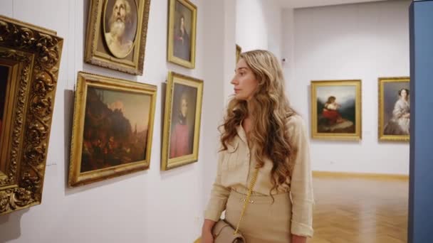 シスナウ モルドヴァ 2023年2月21日 アートギャラリーを歩き 壁に複数の絵画を見ている金髪の女性 スローモーション — ストック動画