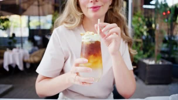 看到一个女人在咖啡店里拿着一杯冰镇的浓缩浓缩咖啡 喝着马可茶泡沫和稻草 — 图库视频影像