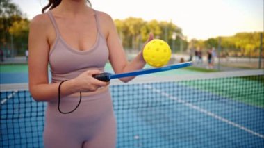 Sarı top ve mavi raketle tenis oynayan bir kadın.