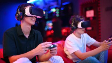 İki genç arkadaş oyun konsolu olarak VR kulaklıkları ve kulaklıklarla oyun konsolu oynuyorlar. Oyun bloknotları kullanarak, fasulye çuvallarının üzerinde otururken konuşup gülümsüyorlar. Mavi ve kırmızı aydınlatma