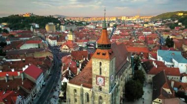 Romanya 'nın eski Brasov şehir merkezindeki Council Square' de gün batımında yapılan canlı gösterinin insansız hava aracı görüntüsü. Siyah Kilise, bir sürü insan, eski konut binaları, uzaktaki yeşil tepeler.