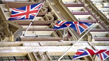 Londra şehir merkezindeki bir binanın cephesinde bulunan Birleşik Krallık bayraklarının dikey görüntüsü
