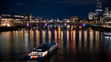 Londra, İngiltere 'de gece Thames Nehri manzarası. Uzakta yüzen tekne, köprüler ve Tower Bridge, Parça gökdeleni ve her iki taraftaki diğer binalar, bir sürü aydınlatma