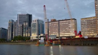 Günbatımında Thames Nehri 'nde yüzen bir tekneden Londra manzarası, İngiltere. Nehir kıyısındaki baraj sokağındaki modern yerleşim yerleri.