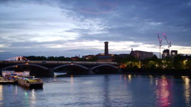 Akşamları Londra şehri, Birleşik Krallık. Thames nehri, köprüde hareket eden tren, yeşil ve aydınlık binalar.