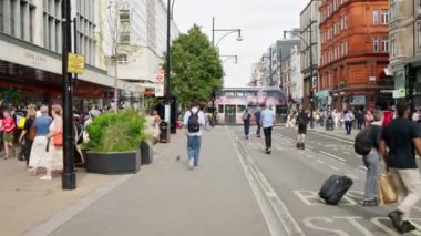 LONDRA, BİRLİK KINGDOM - 11 Ağustos 2023: Birden fazla yürüyen insan, klasik binalar ve yeşillik.