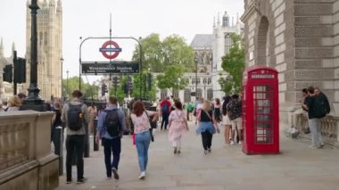 Londra, UNITED KINGDOM - 11 Ağustos 2023: Yürüyen insanlar, klasik binalar ve hareket eden arabalar, arka planda Westminster Sarayı ve Abbey ile şehir merkezi manzarası