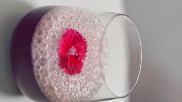 アルコールと泡 上の赤い花と紫色のカクテルでガラスを閉じる — ストック動画
