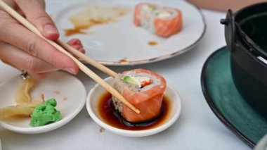 Bir kadının yemek çubuğu kullanarak soya soslu bir kaseden Philadelphia dürümü alışının yavaş çekim görüntüsü.