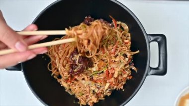 Yemek çubuklarıyla Çin eriştesini kaseden alan bir kadının yavaş çekim dikey görüntüsü. Yavaş çekim