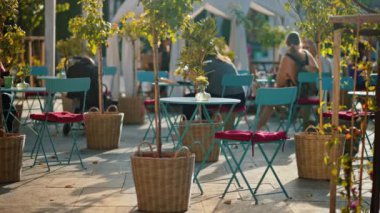 Moldova 'nın başkenti Chisinau' daki Eminescu meydanı gün batımında görülüyor. Bir kafe, dekorasyon ve yeşillik yakınında birden fazla sandalye ve masa.